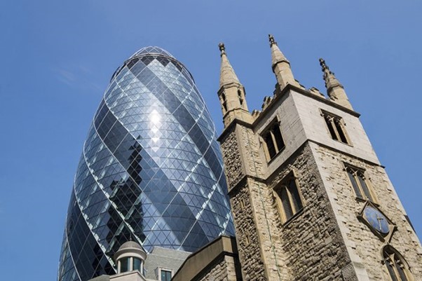 The Swiss Re building known as The Gherkin towering above St Andrew Undershaft in the City of London. (Credit: Ed Rhodes. Discover Britain.)